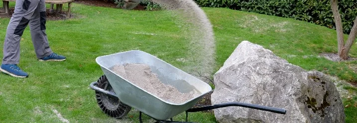 Person verteilt Sand mit Schaufel